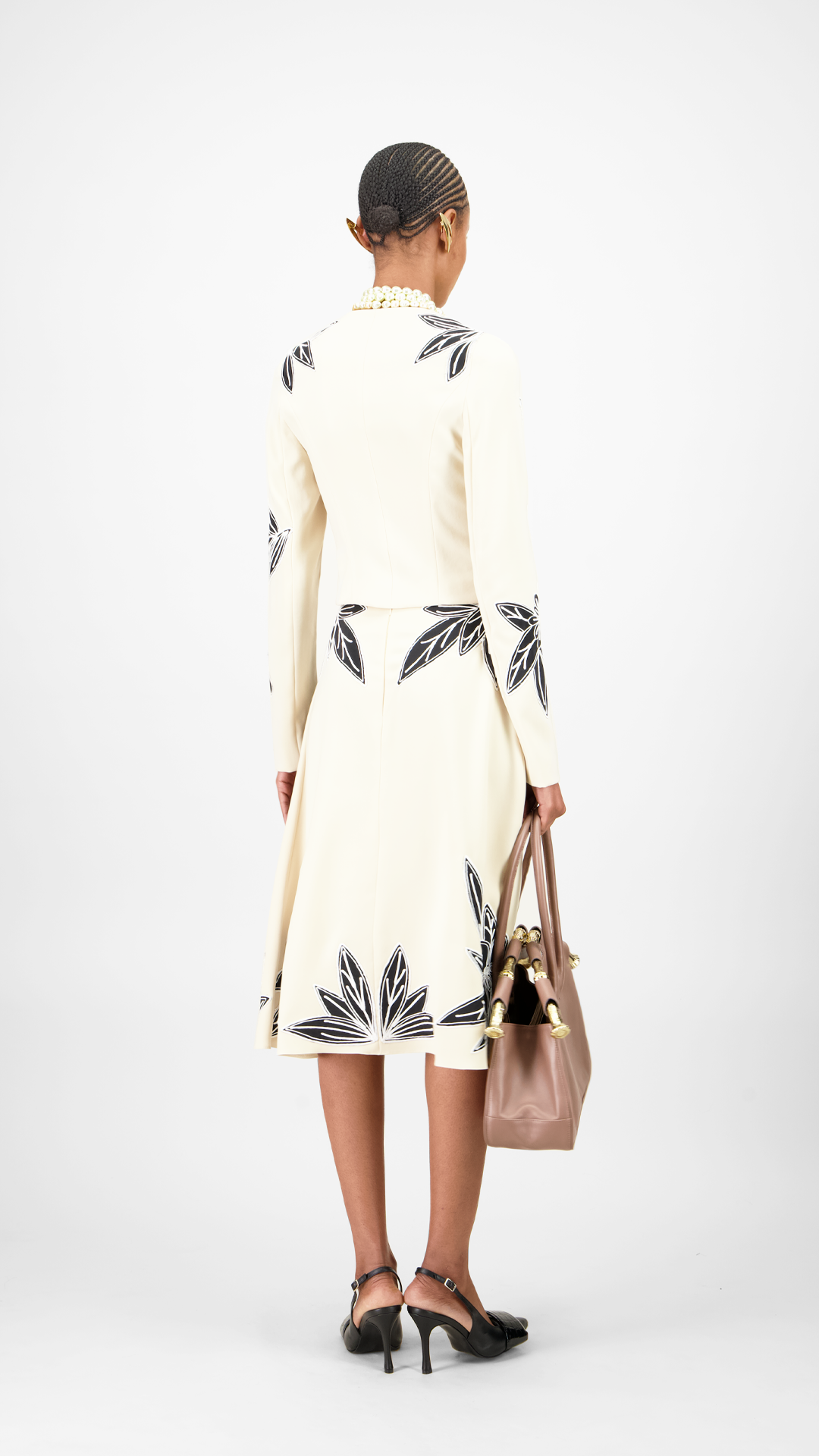 Woman wearing a floral set jacket and skirt with black leaf patterns