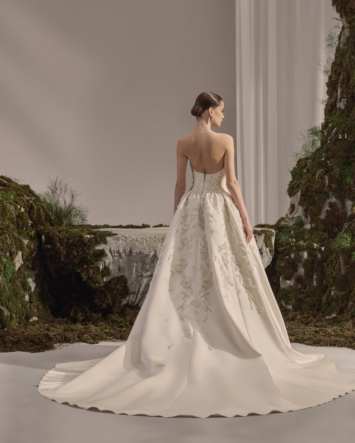 Strapless bridal gown with a structured embroidered bodice, voluminous satin skirt and sheer embellished veil.