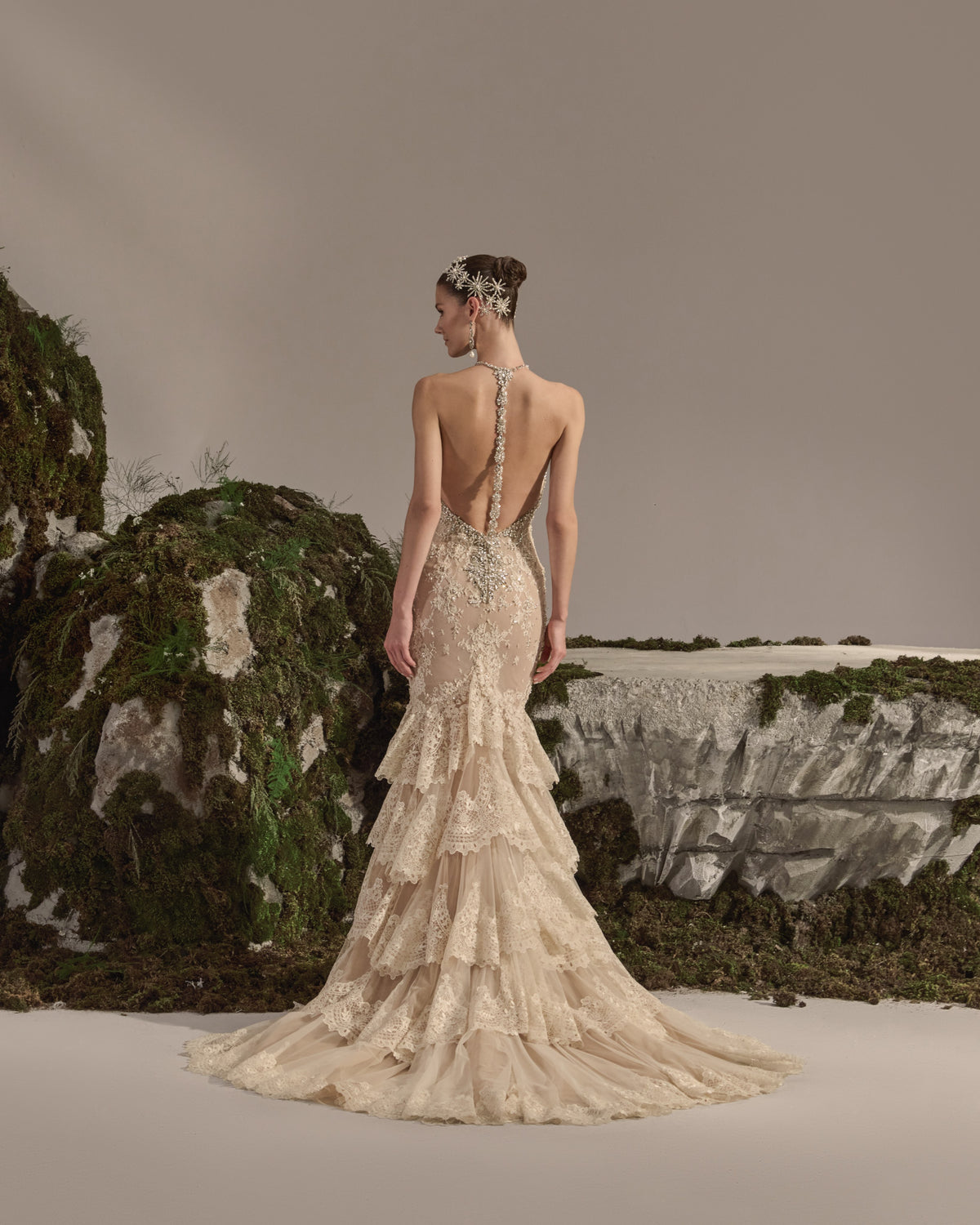Halter-neck bridal gown with intricate embellishment, fitted silhouette, tiered lace skirt and sheer veil.
