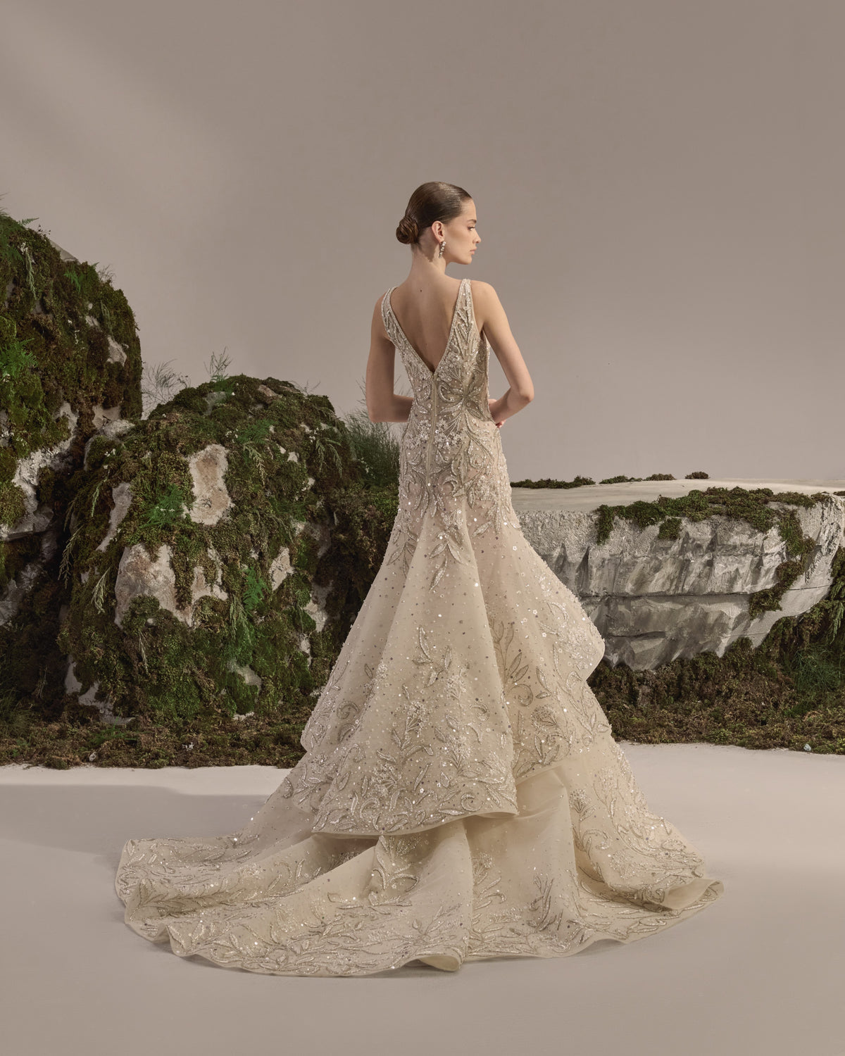 Bridal gown with an embellished sculpted corset bodice, delicate shoulder details, a flowing beaded tulle skirt, and a sheer veil.
