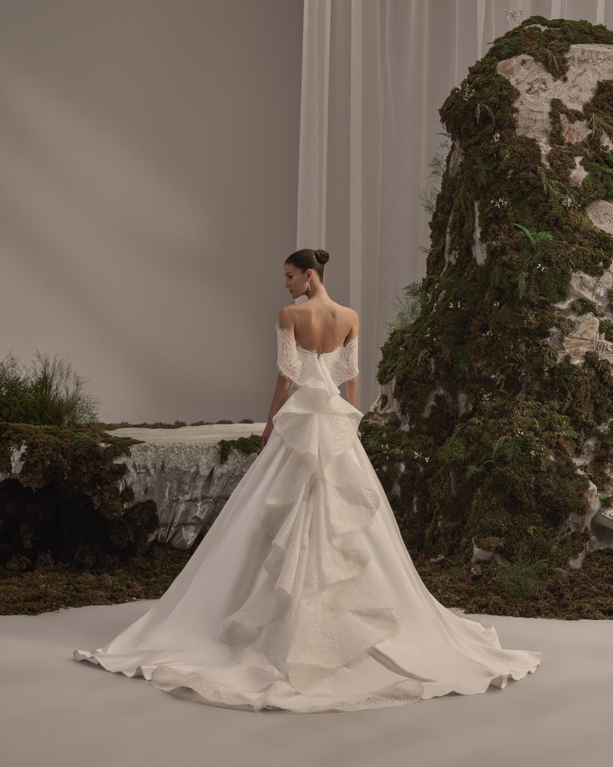 Off-shoulder bridal gown with delicate lace detailing, a fitted sculpted bodice and a flowing train with a sheer veil.