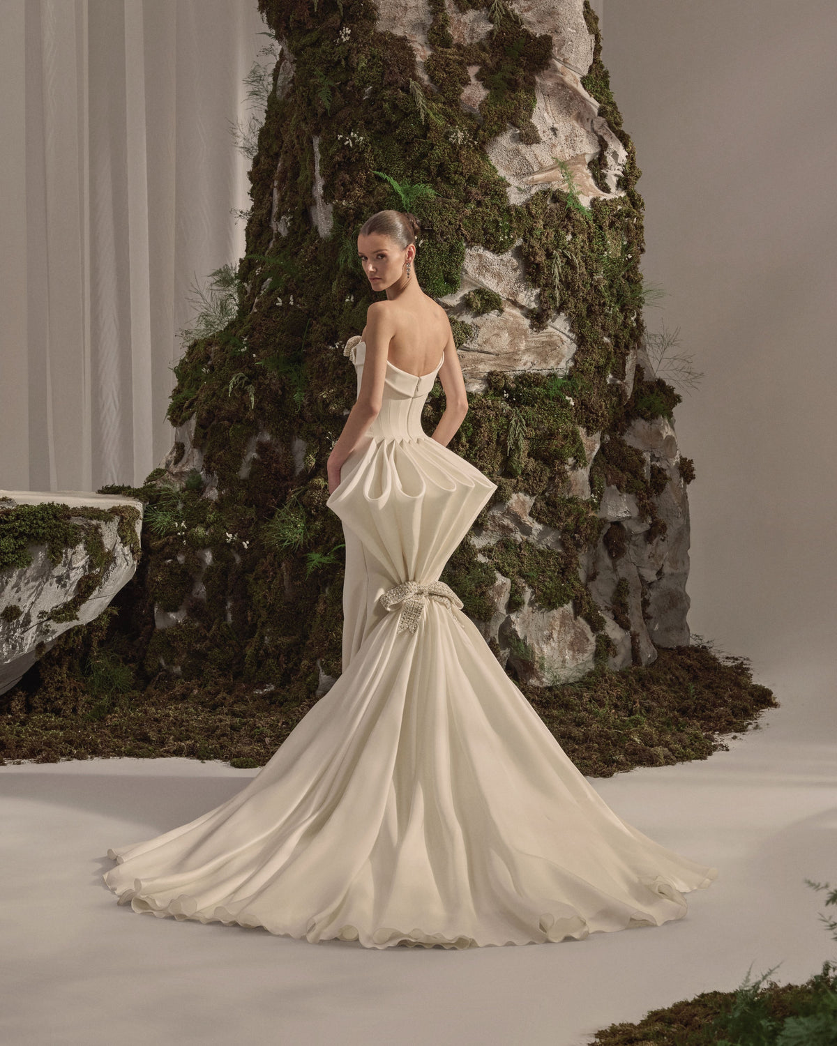 Strapless bridal gown with an embellished bow neckline, fitted sculpted silhouette and flowing train with a sheer veil.