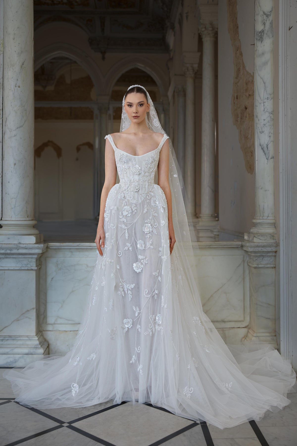 Bridal gown with a scoop neckline, floral embroidery and appliqués, flowing tulle skirt and delicate embroidered veil.