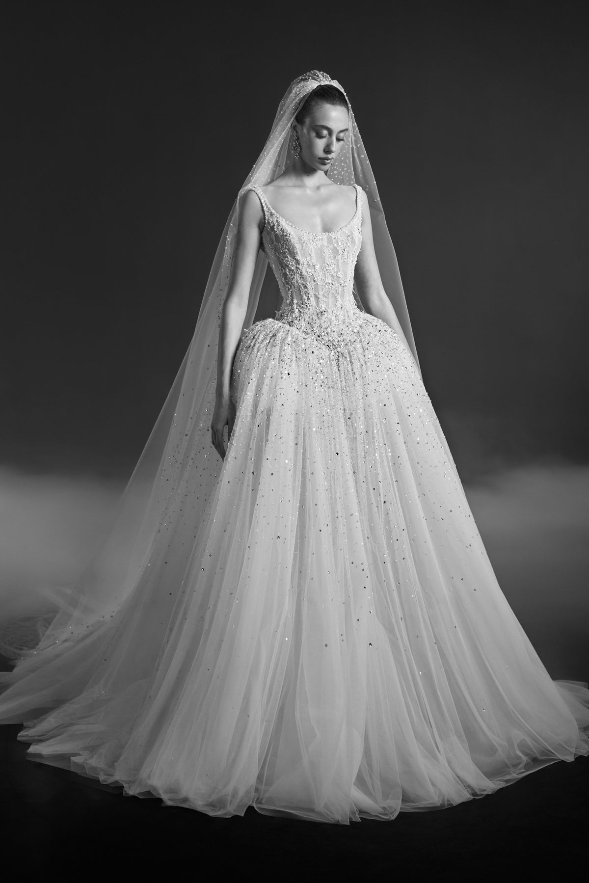 Off-white scoop-neck bridal gown with embellished bodice, voluminous tulle skirt and long matching veil.
