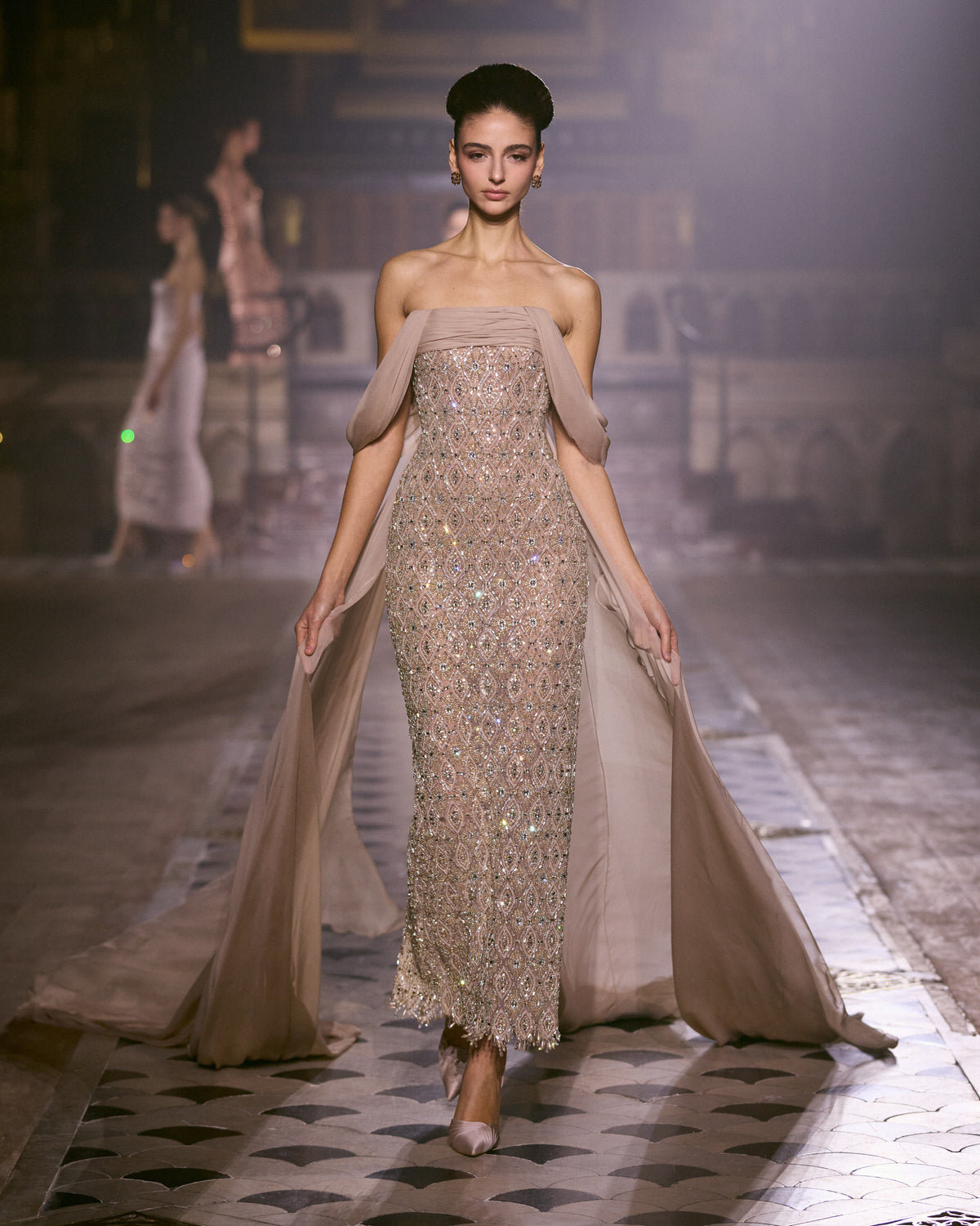 Blush pink fitted couture dress with all-over crystal embellishment and flowing draped panels.