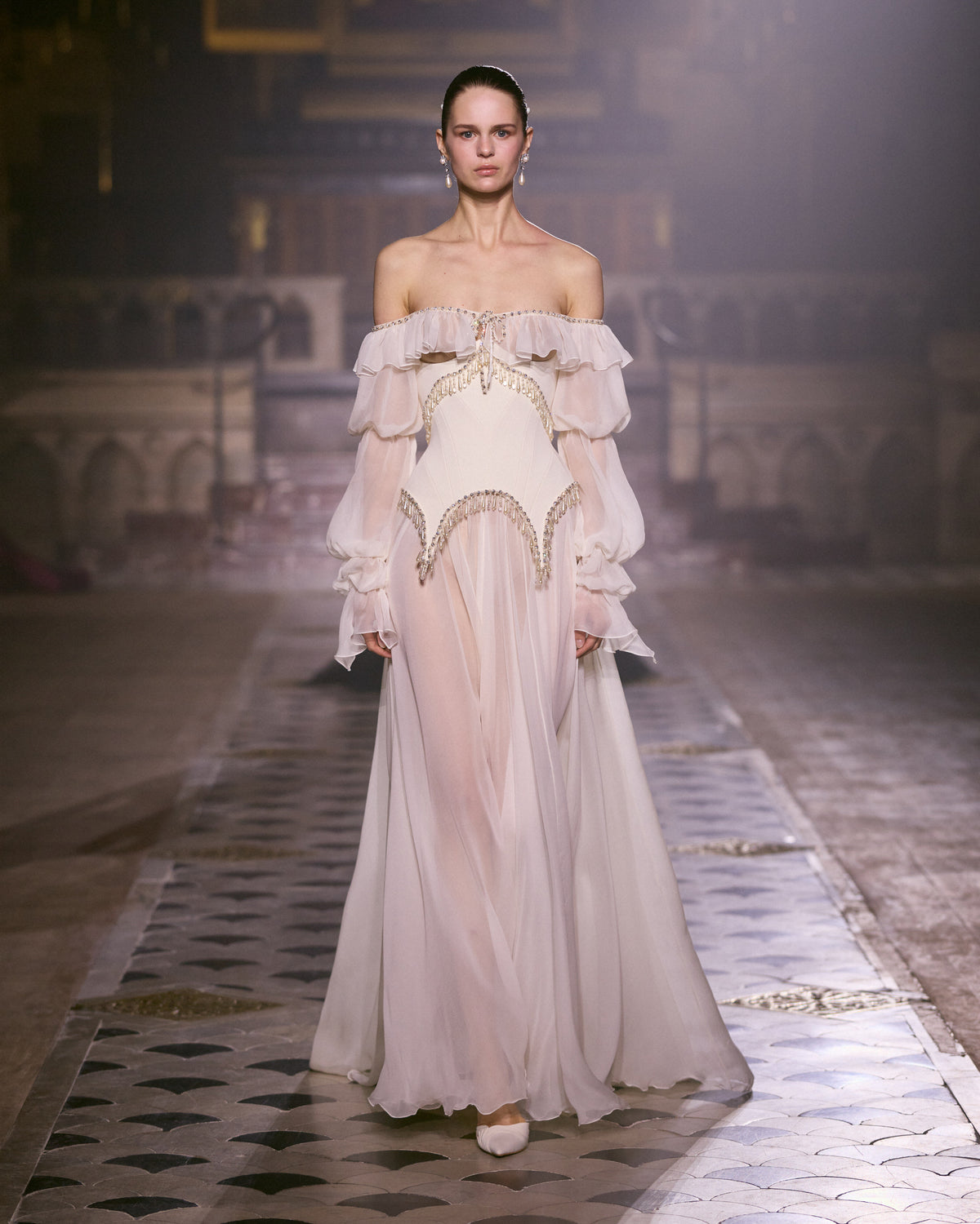 Ivory chiffon couture gown with off-shoulder ruffles, sheer voluminous sleeves and delicate crystal embellishment.