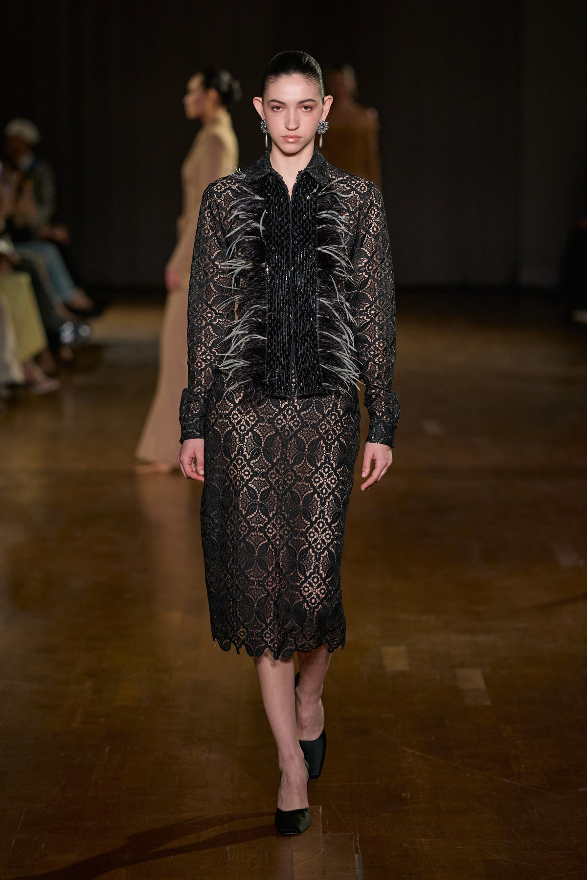 Black lace long-sleeve shirt with feather and sequin detailing, paired with a matching floral lace midi skirt.