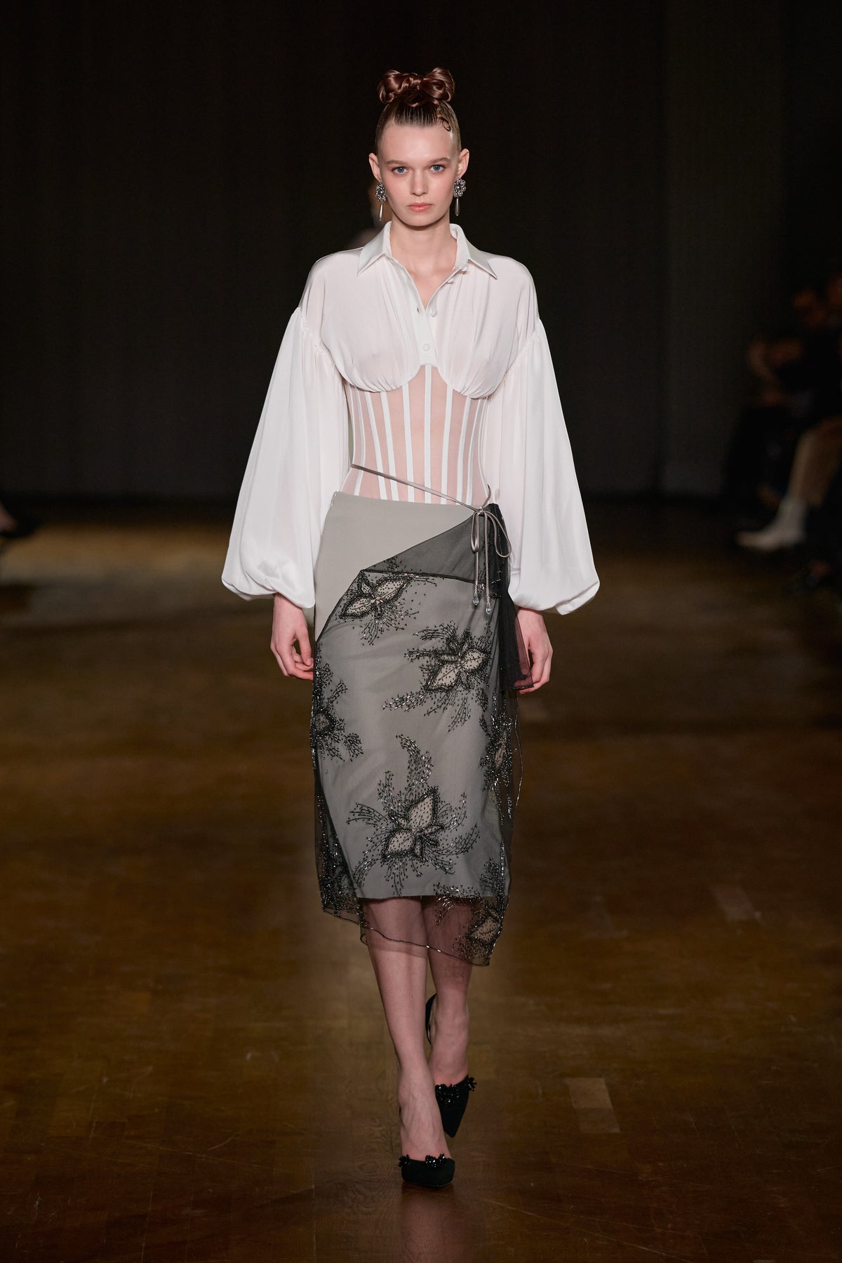White corset shirt with voluminous sleeves paired with a grey asymmetric midi skirt featuring black floral embroidered tulle.