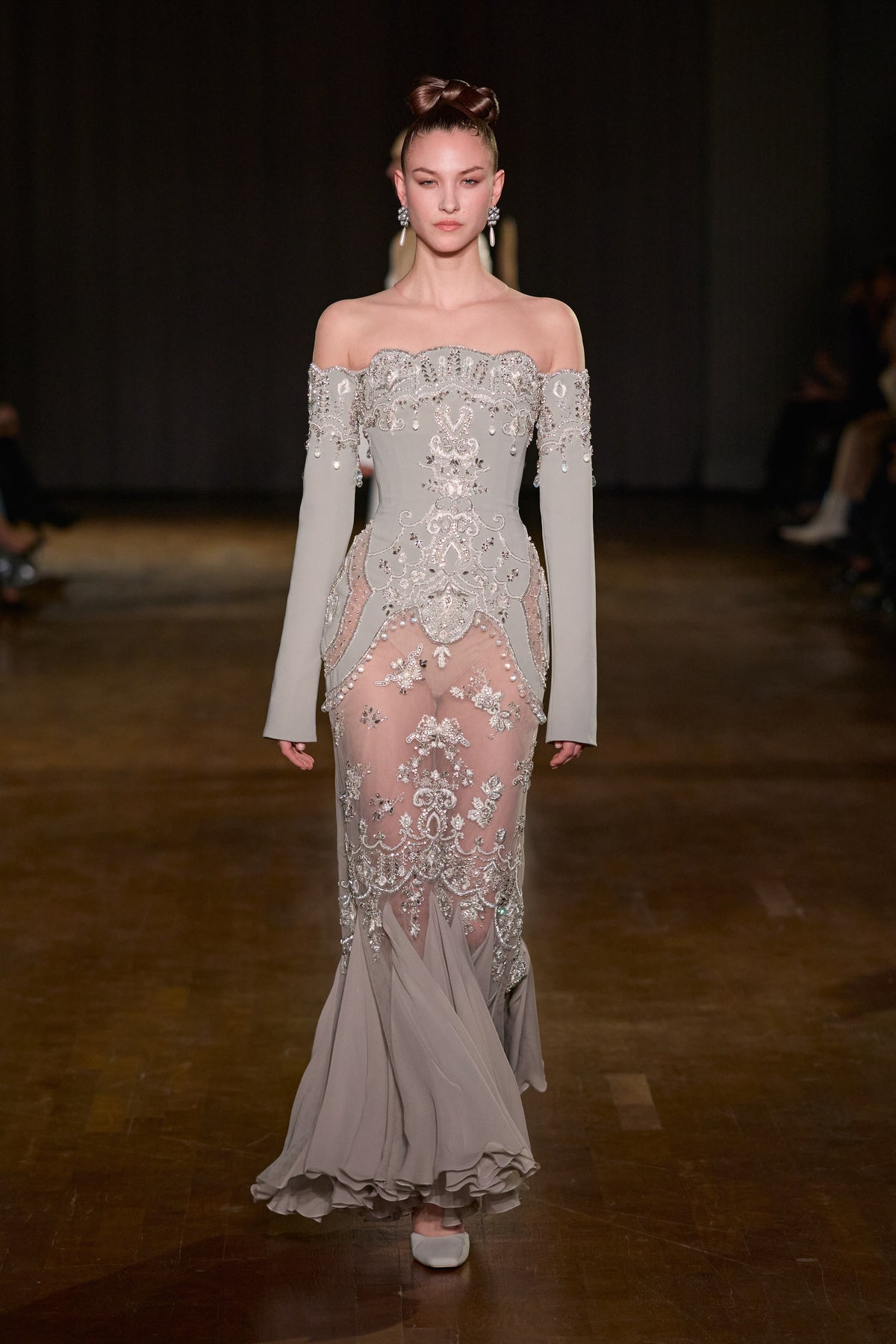 Grey off-shoulder floor-length gown with long sleeves, crystal embroidery, sheer detailing and flowing flared hem.