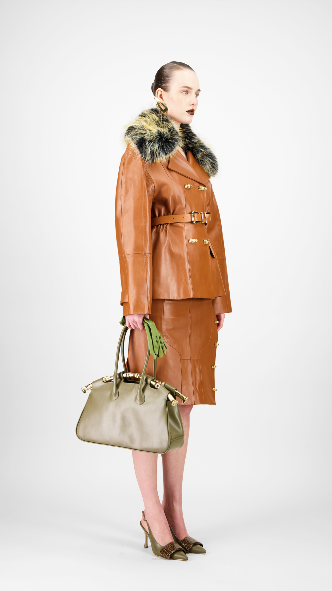 Woman wearing a brown leather coat with fur trim and holding a matching handbag.