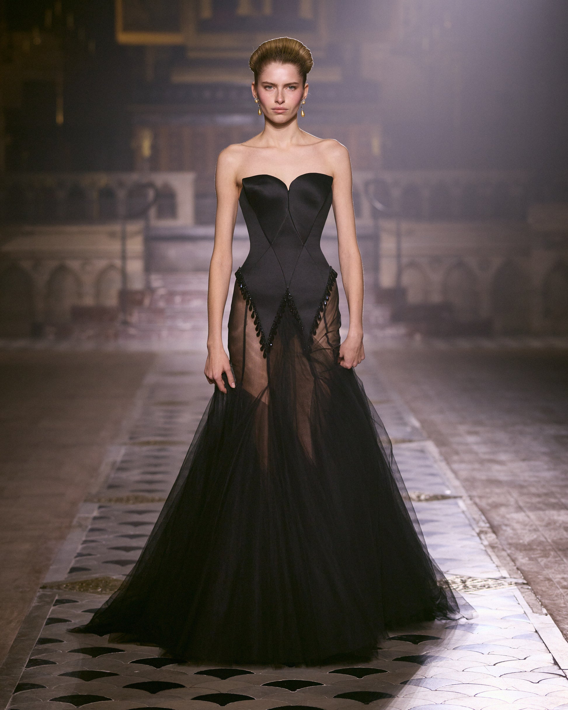 Model walks the runway in Georges Hobeika Couture Spring–Summer 2026 Look 44, wearing a black strapless gown with sheer panels.