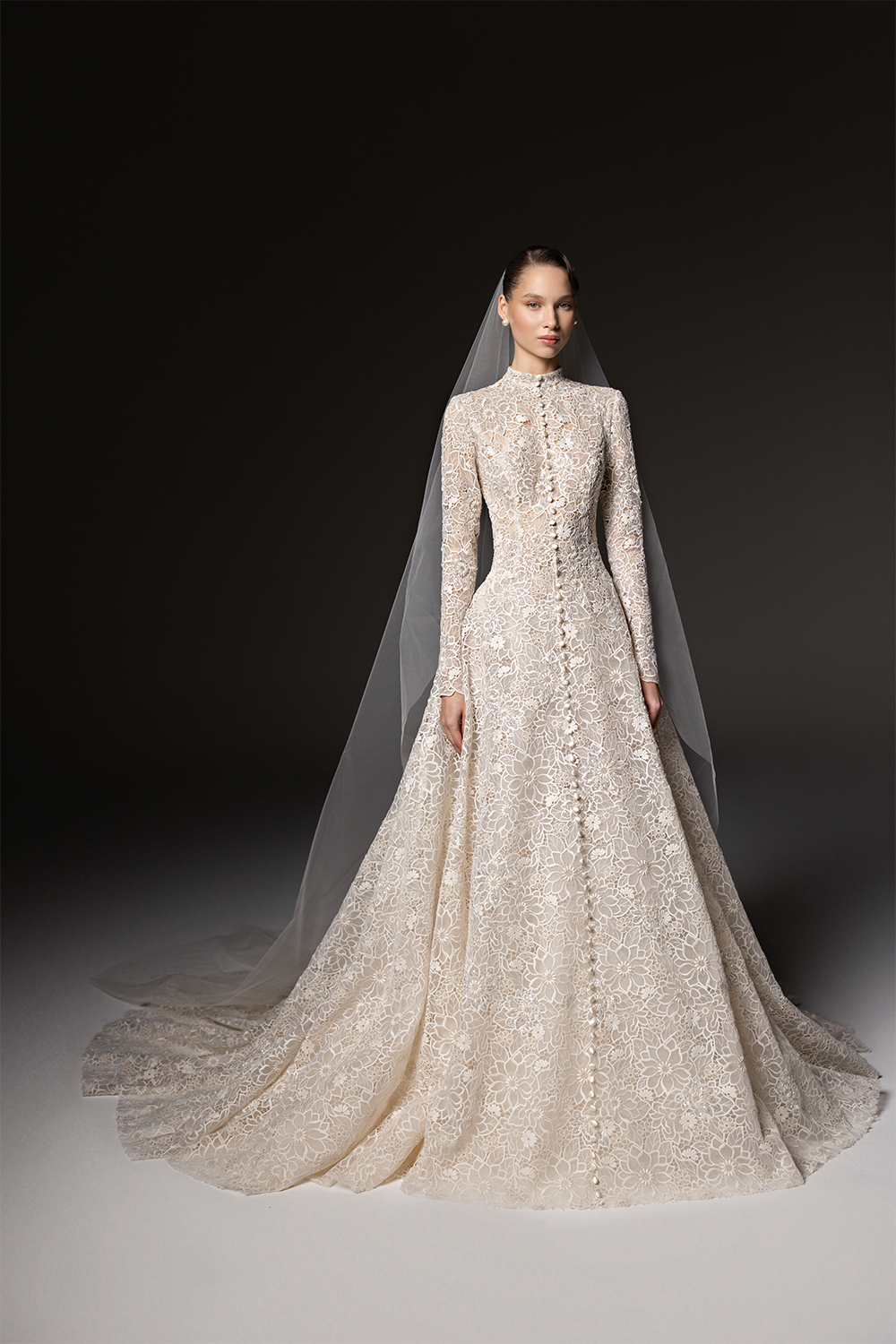 High-neck bridal gown in floral lace with long sleeves, delicate embellishment and a full floor-length skirt with train.
