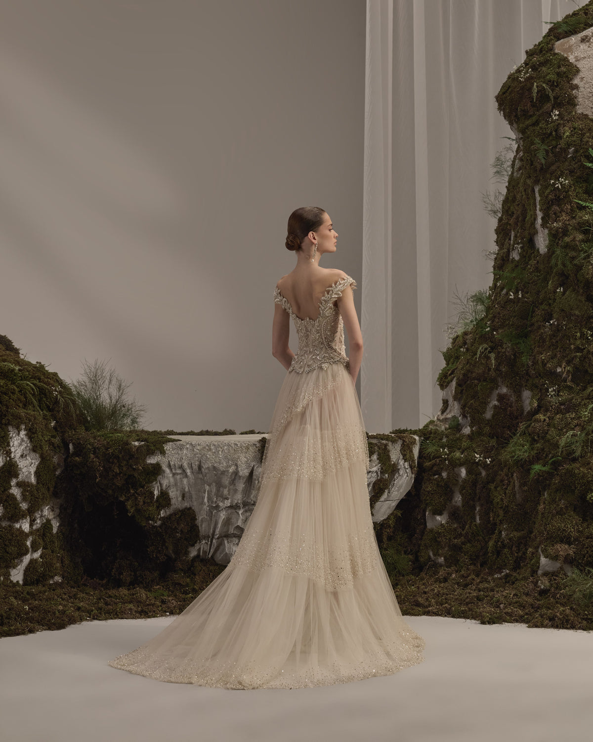 Bridal gown with an embellished sculpted corset bodice, delicate shoulder details, flowing beaded tulle skirt and sheer veil.