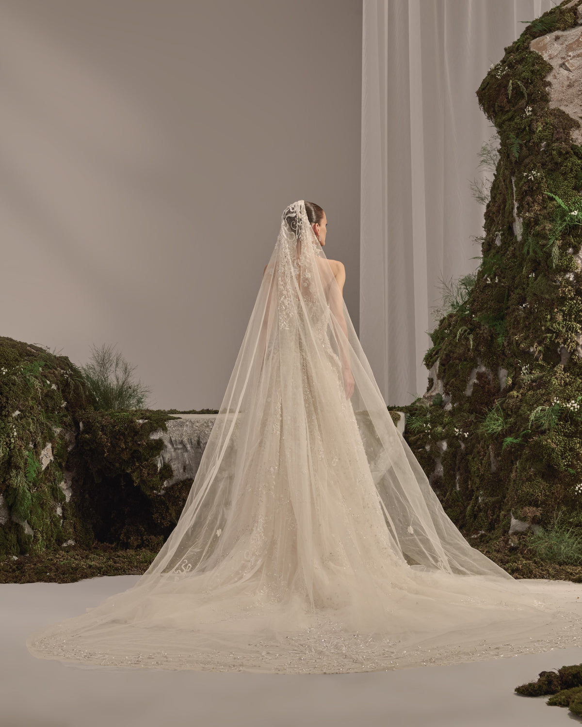 Bridal gown with a bateau neckline, short embellished sleeves, intricately embroidered bodice, fitted waist and flowing beaded tulle skirt with train.