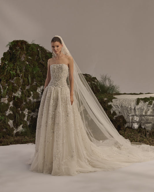 Bridal gown with a bateau neckline, short embellished sleeves, intricately embroidered bodice, fitted waist and flowing beaded tulle skirt with train.