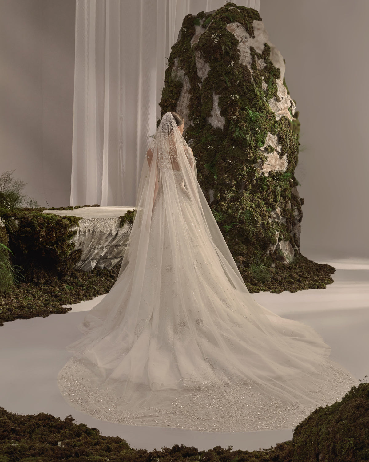 Bridal gown with delicate straps, a sculpted embellished corset bodice, flowing beaded tulle skirt and sheer veil.
