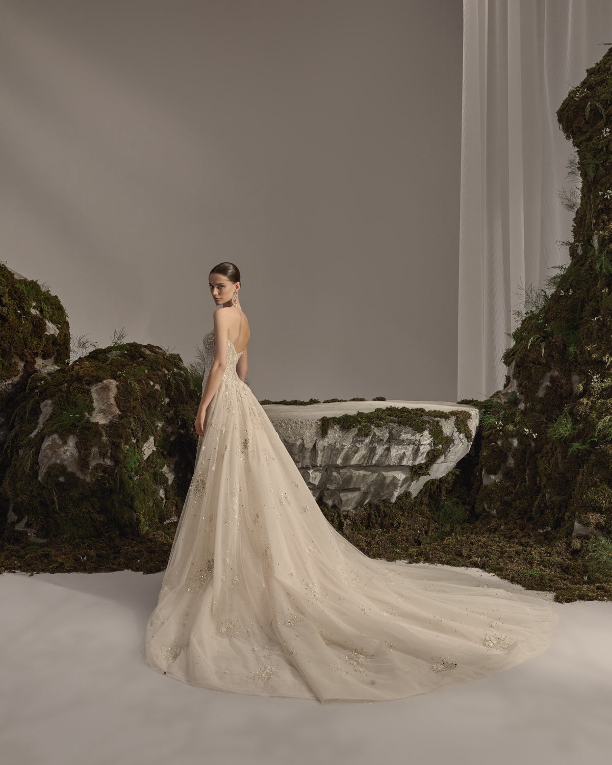 Strapless bridal gown with intricate embellishment, sculpted fitted silhouette, flowing tulle overskirt and sheer veil.