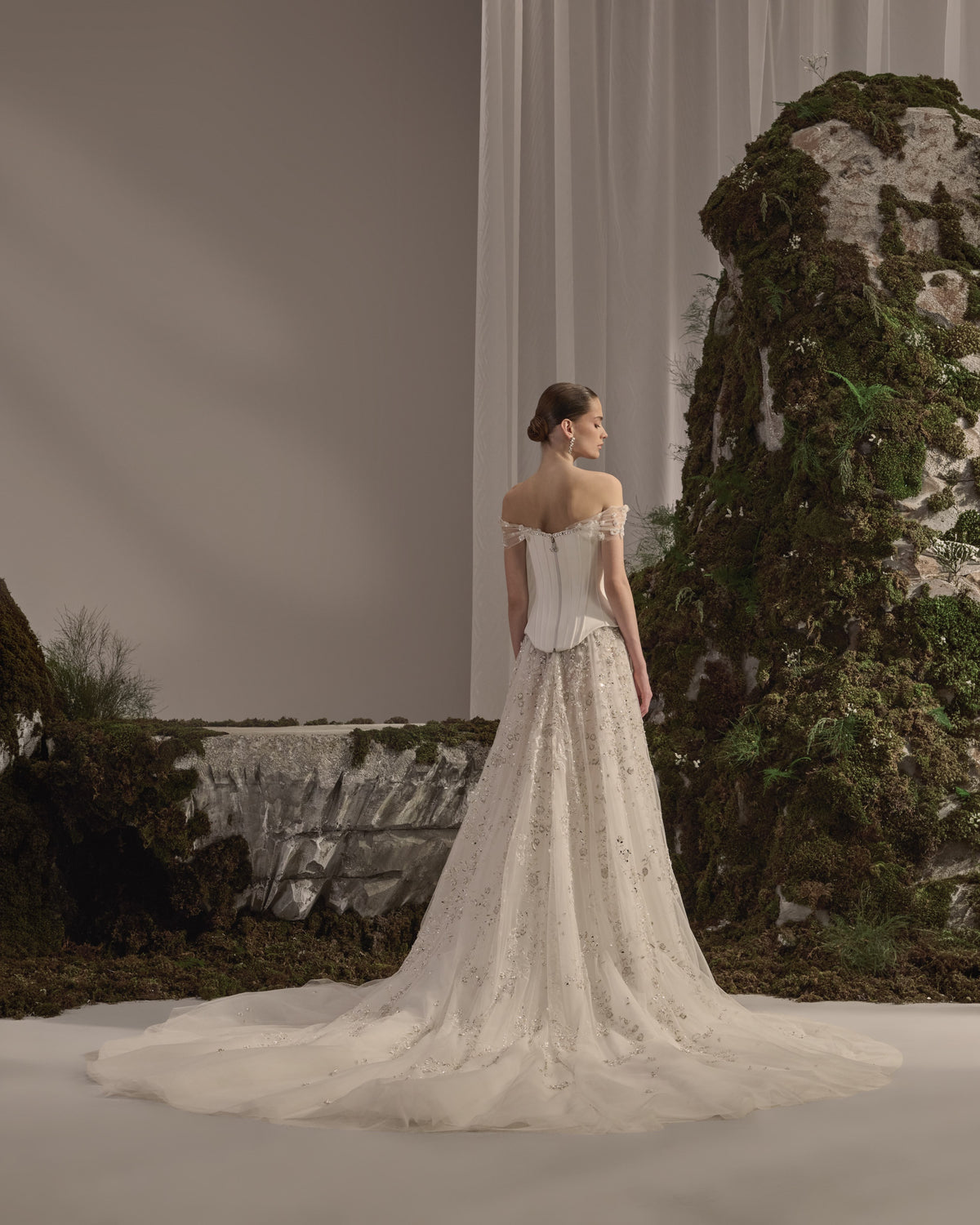 Off-shoulder bridal gown with a structured corset bodice, delicate embroidery, flowing tulle skirt and sheer veil.