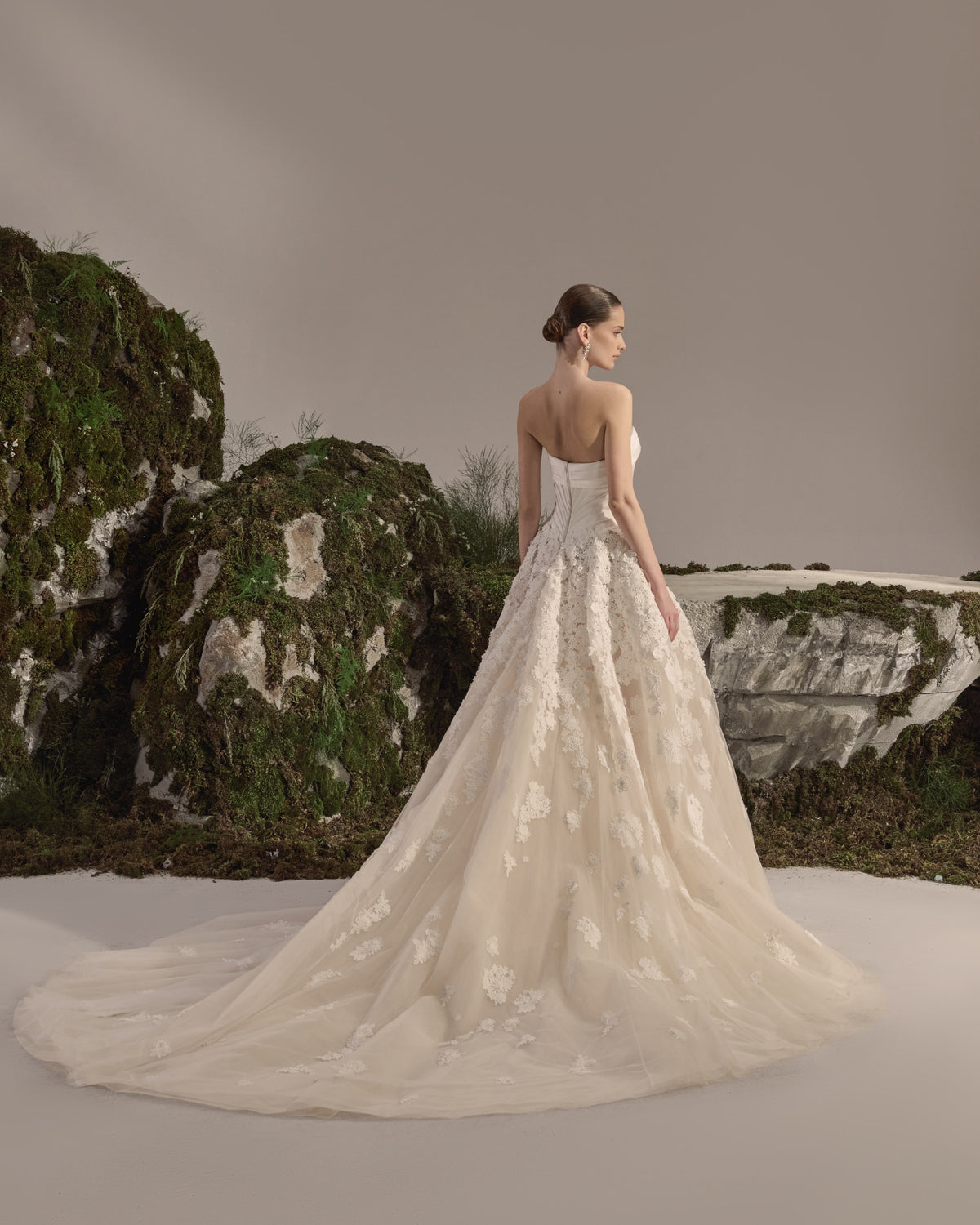 Strapless bridal gown with a sculpted corset bodice, voluminous tulle skirt, delicate lace appliqués and sheer veil.