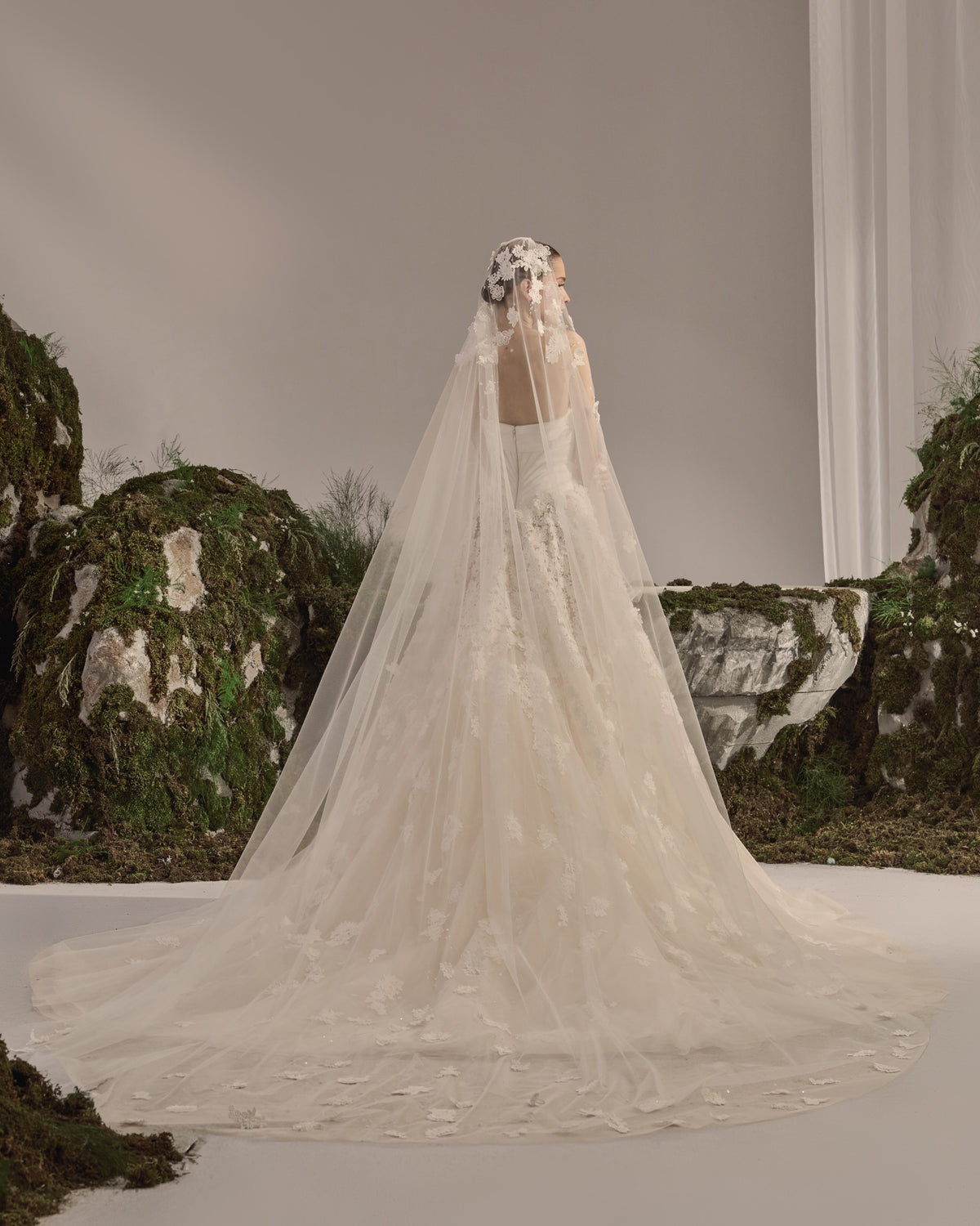 Strapless bridal gown with a sculpted corset bodice, voluminous tulle skirt, delicate lace appliqués and sheer veil.