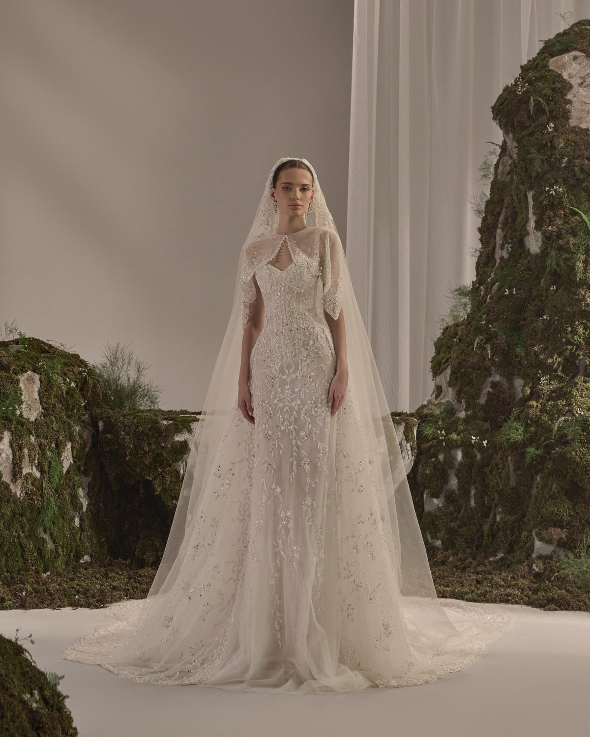 Embellished fitted bridal gown with a detachable sheer embroidered bolero and flowing veil.
