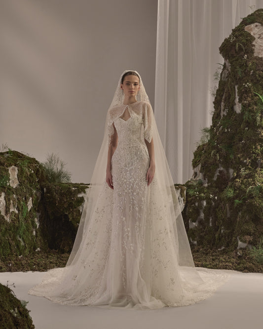 Embellished fitted bridal gown with a detachable sheer embroidered bolero and flowing veil.