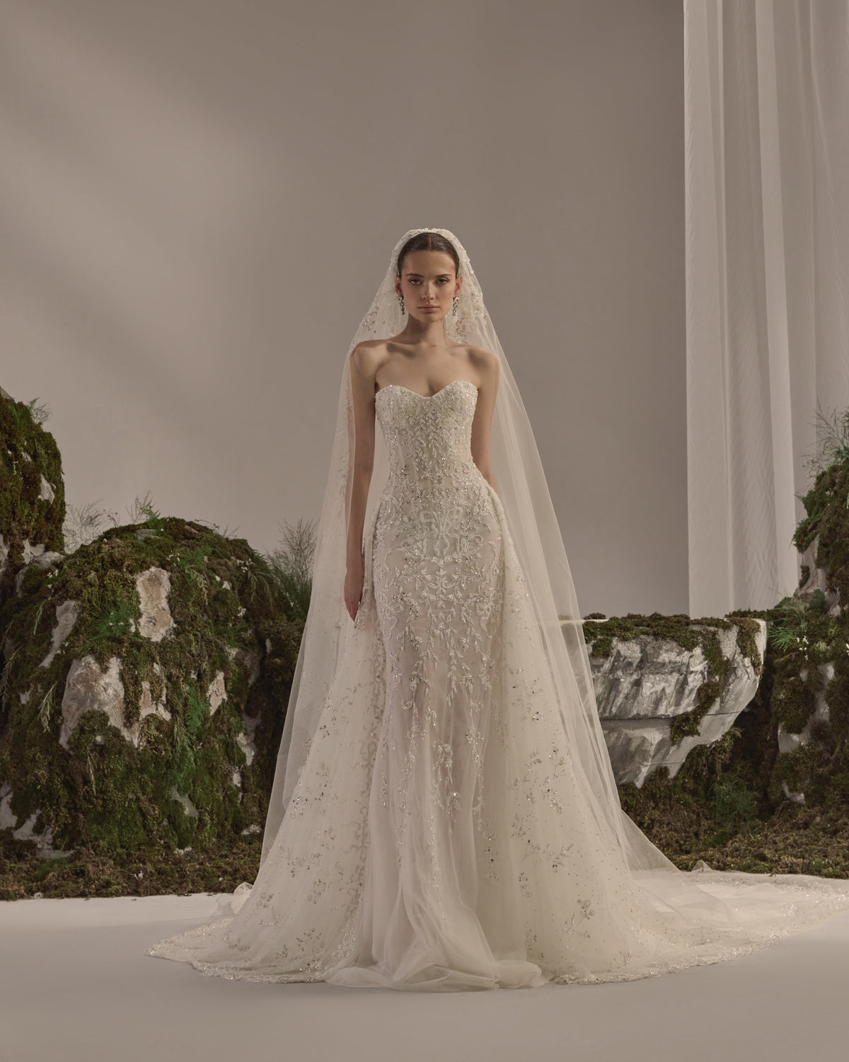 Embellished fitted bridal gown with a detachable sheer embroidered bolero and flowing veil.