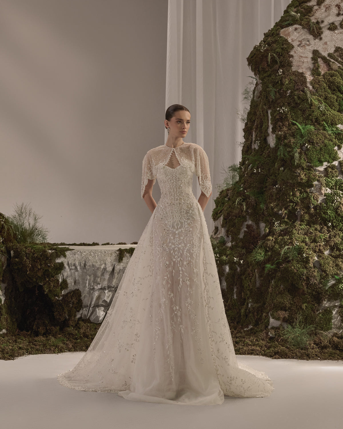 Embellished fitted bridal gown with a detachable sheer embroidered bolero .
