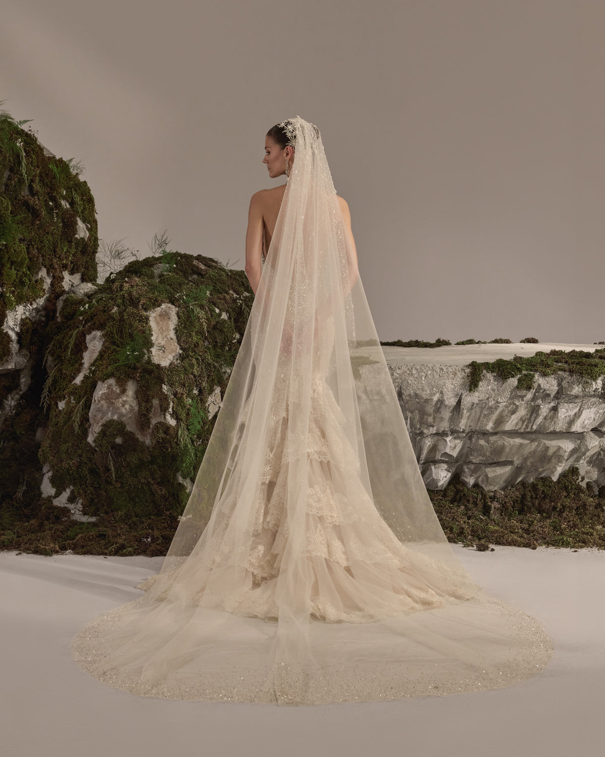 Halter-neck bridal gown with intricate embellishment, fitted silhouette, tiered lace skirt and sheer veil.