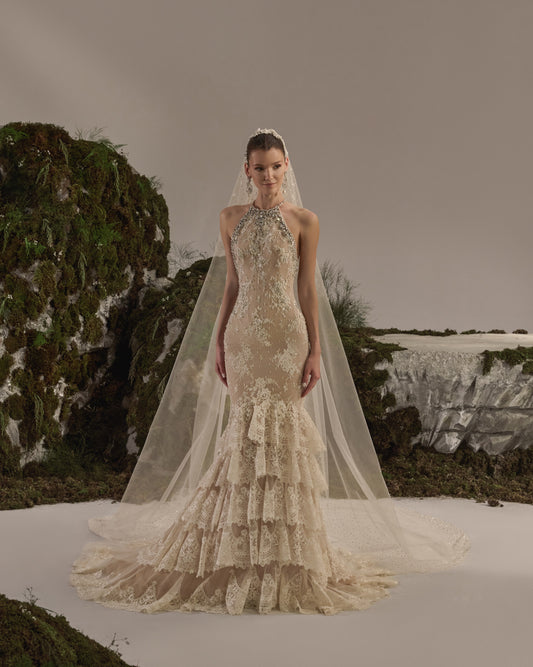 Halter-neck bridal gown with intricate embellishment, fitted silhouette, tiered lace skirt and sheer veil.