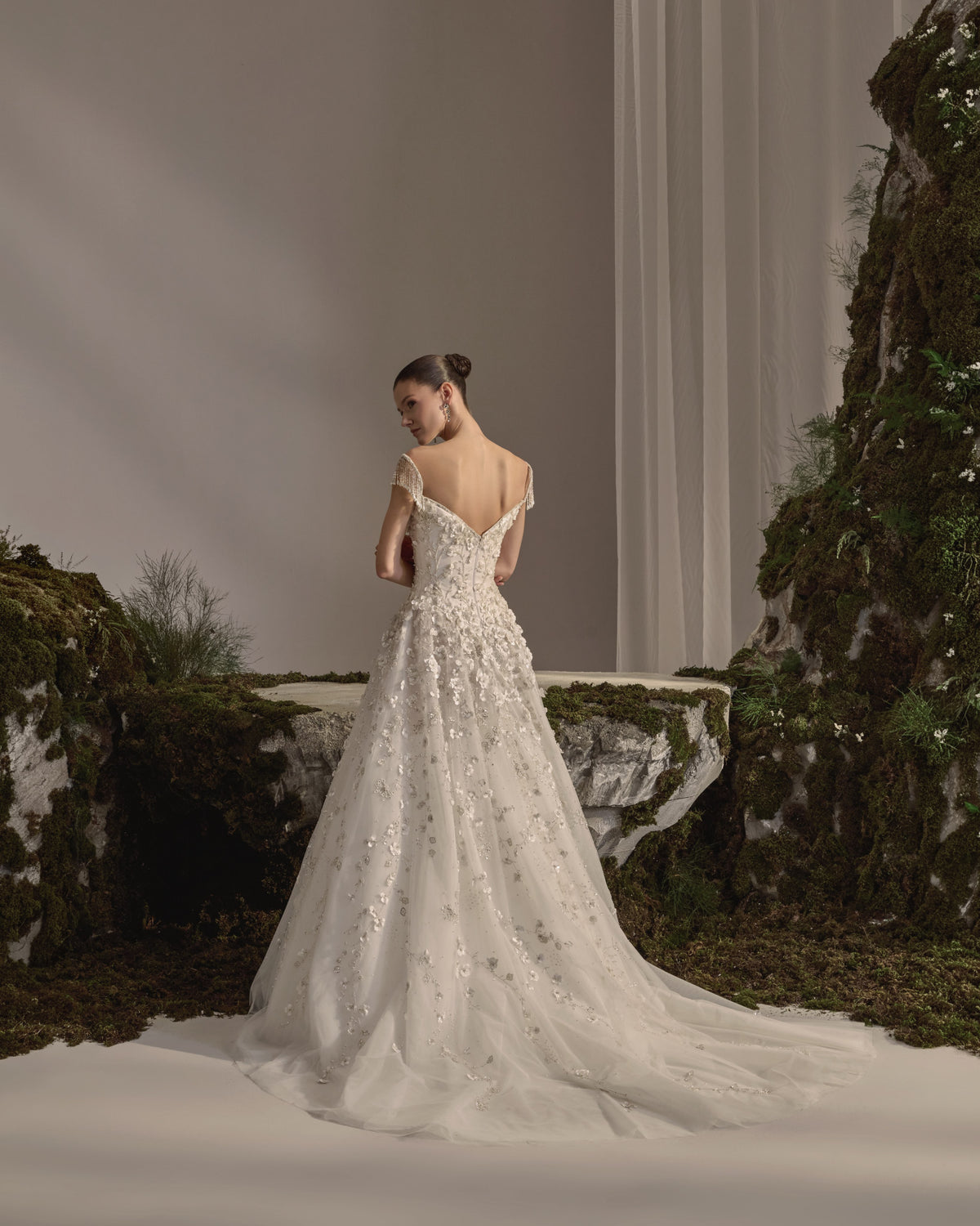 Bridal gown with a sculpted bodice, beaded cap sleeves, floral embellishment, flowing tulle skirt and sheer veil.