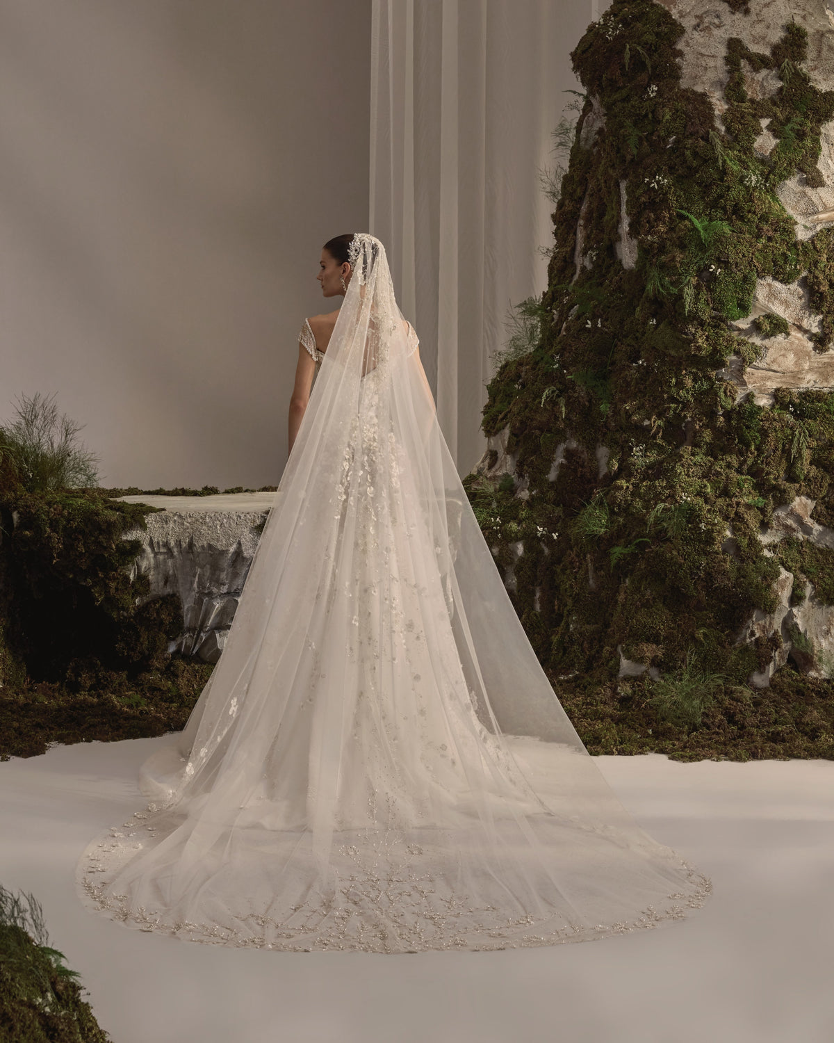 Bridal gown with a sculpted bodice, beaded cap sleeves, floral embellishment, flowing tulle skirt and sheer veil.