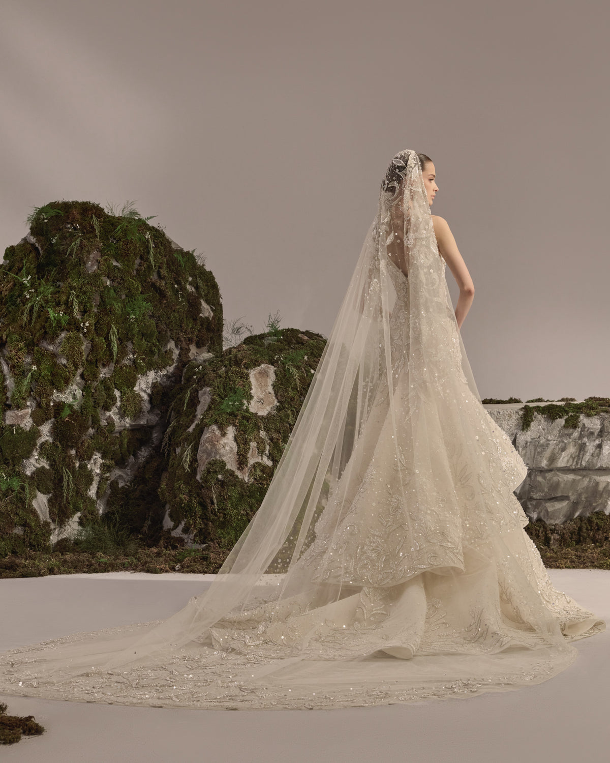 Bridal gown with an embellished sculpted corset bodice, delicate shoulder details, a flowing beaded tulle skirt, and a sheer veil.
