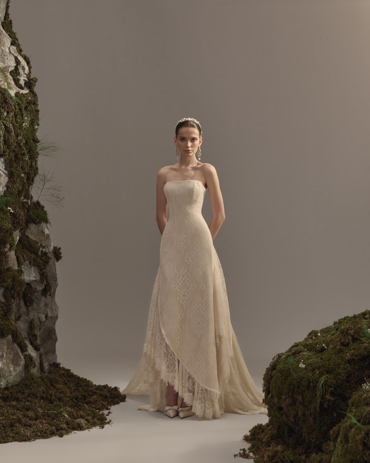 Strapless bridal gown in delicate lace with a fitted bodice, flowing asymmetrical skirt and soft train.