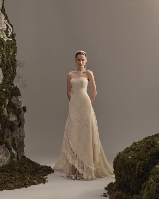 Strapless bridal gown in delicate lace with a fitted bodice, flowing asymmetrical skirt and soft train.