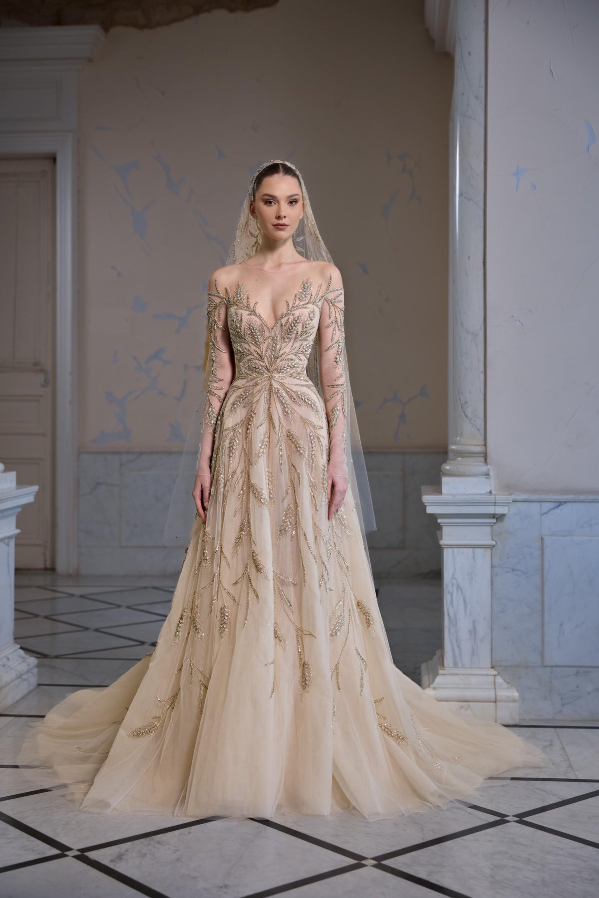 Off-shoulder tulle bridal gown with sheer long sleeves, botanical embroidery, a fitted bodice and flowing floor-length skirt.