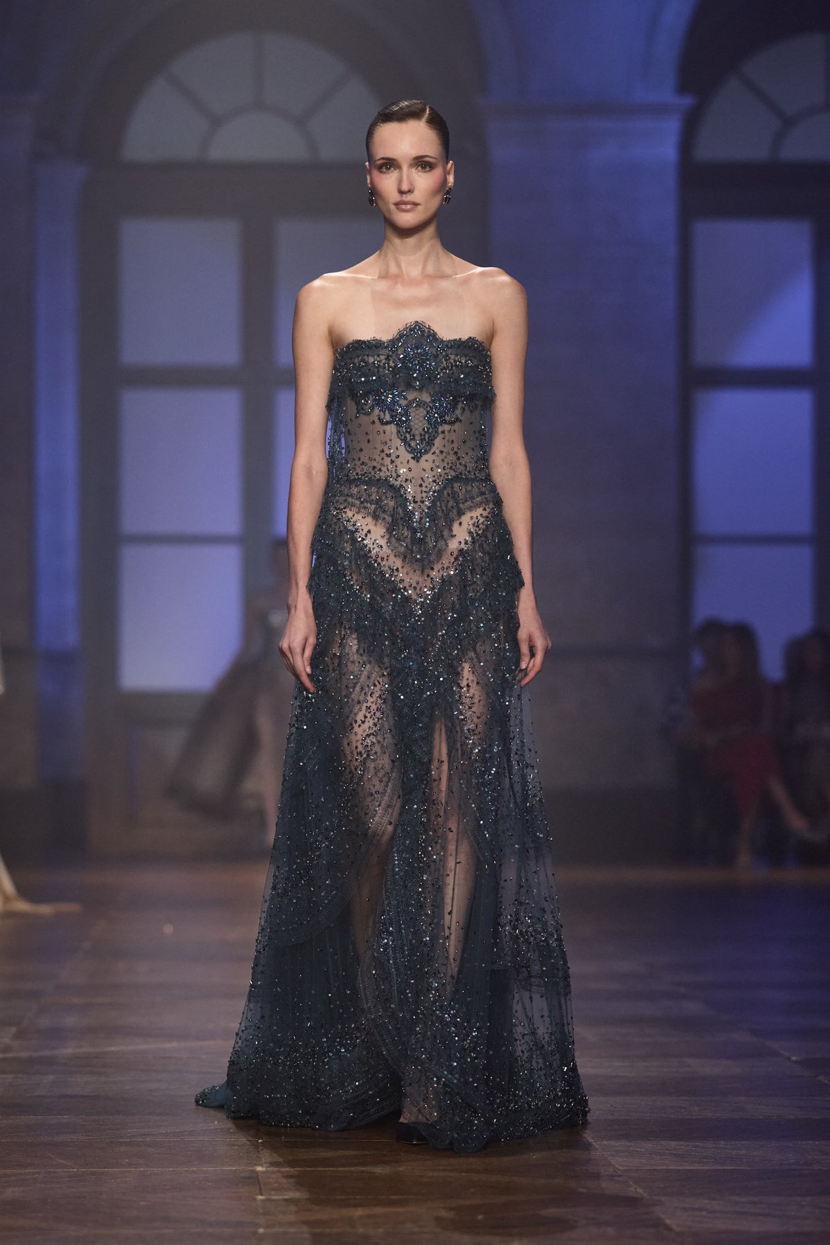 Strapless midnight blue sheer tulle gown with intricate crystal embellishments and sculpted embroidered detailing.