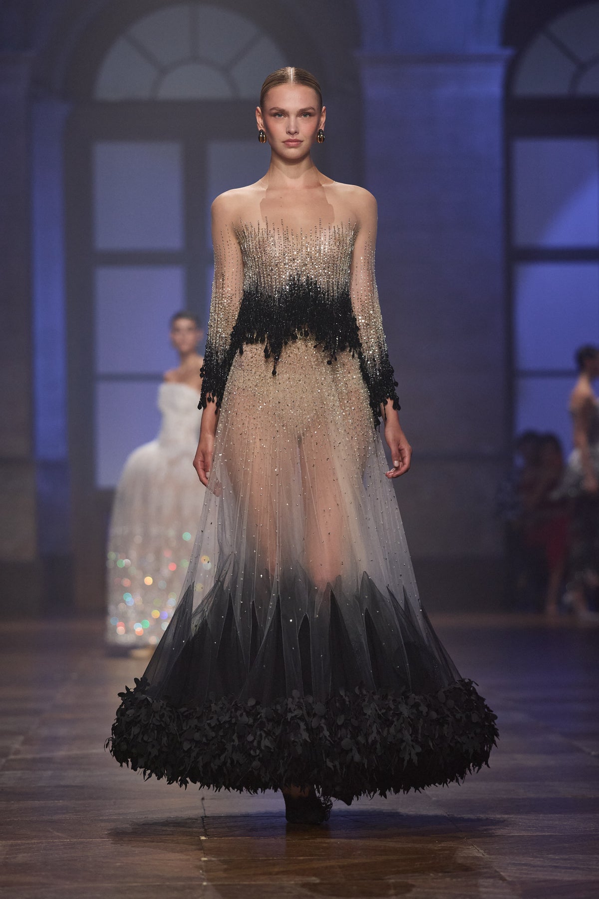 Black embellished couture jacket paired with a sheer crystal-embroidered tulle midi skirt featuring a textured black hem.