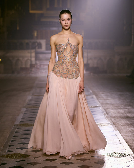 Blush pink couture gown with sculpted crystal-embellished bodice and flowing chiffon skirt.
