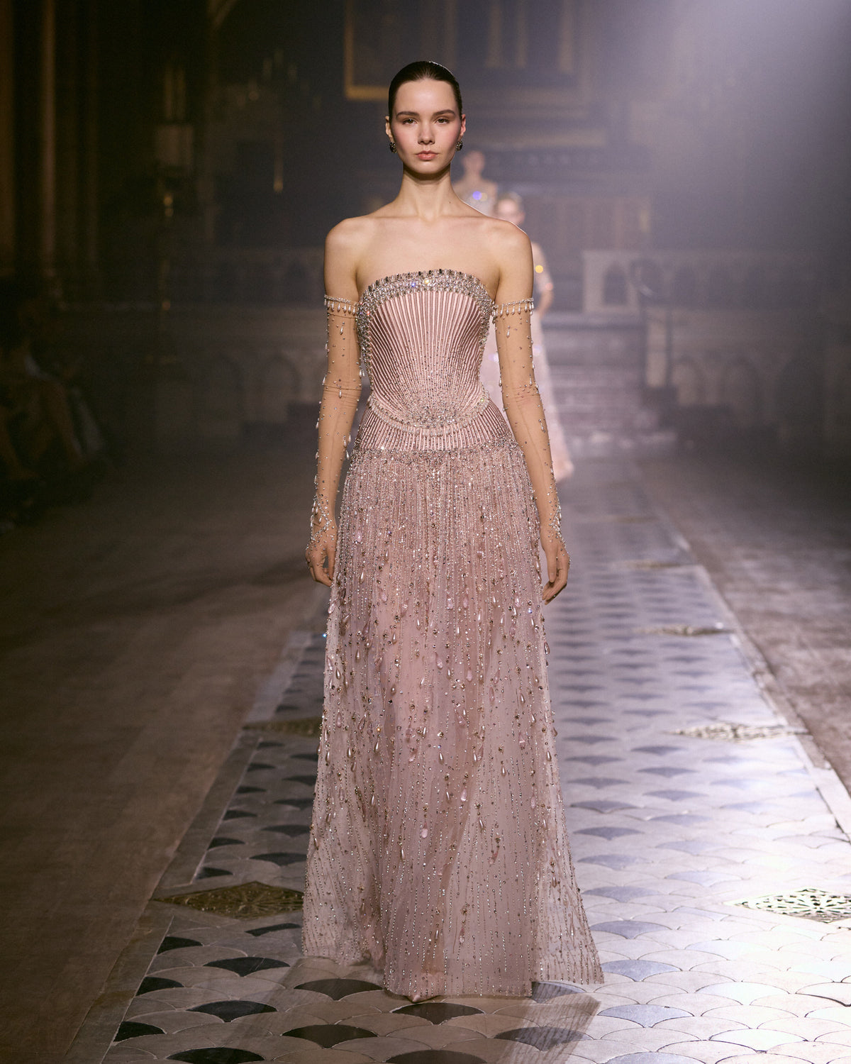 Blush pink strapless couture gown with sculpted bodice, sheer sleeves and intricate crystal embellishment.