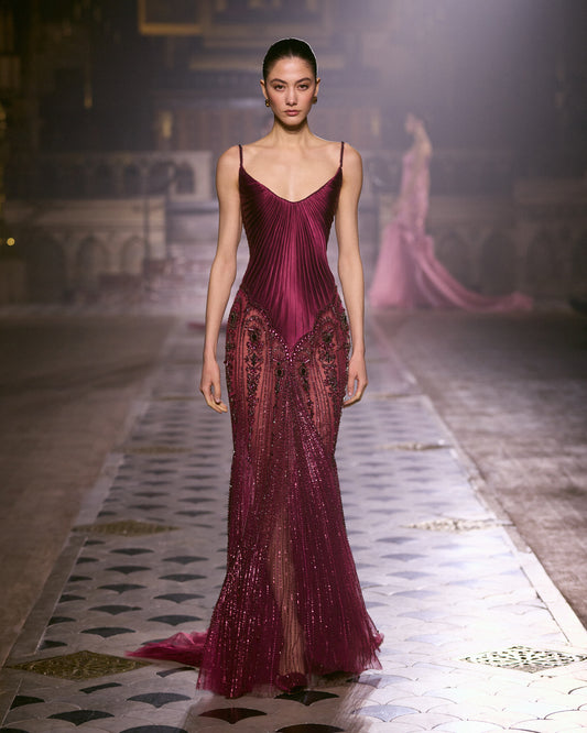 Burgundy couture gown with pleated bodice, delicate straps and intricate crystal embellishments.
