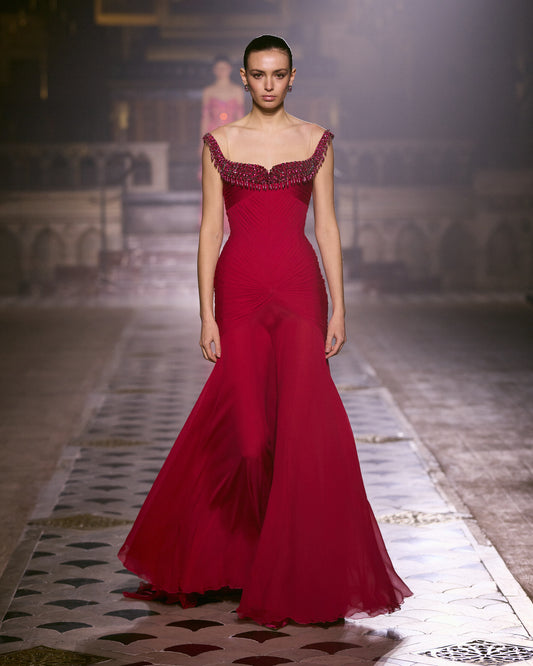 Crimson couture gown with a draped silhouette, flared skirt and crystal-embellished neckline.