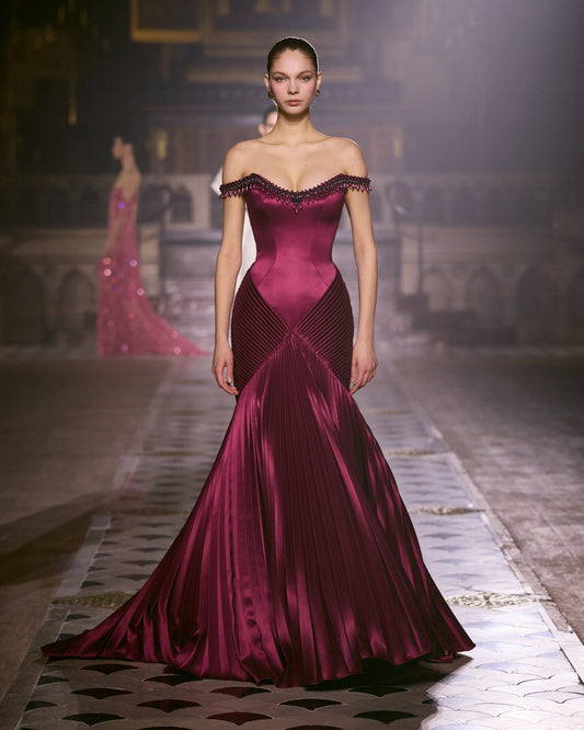 Burgundy off-shoulder couture gown with jeweled neckline, sculpted bodice and pleated satin skirt.