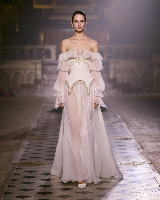 Ivory chiffon couture gown with off-shoulder ruffles, sheer voluminous sleeves and delicate crystal embellishment.