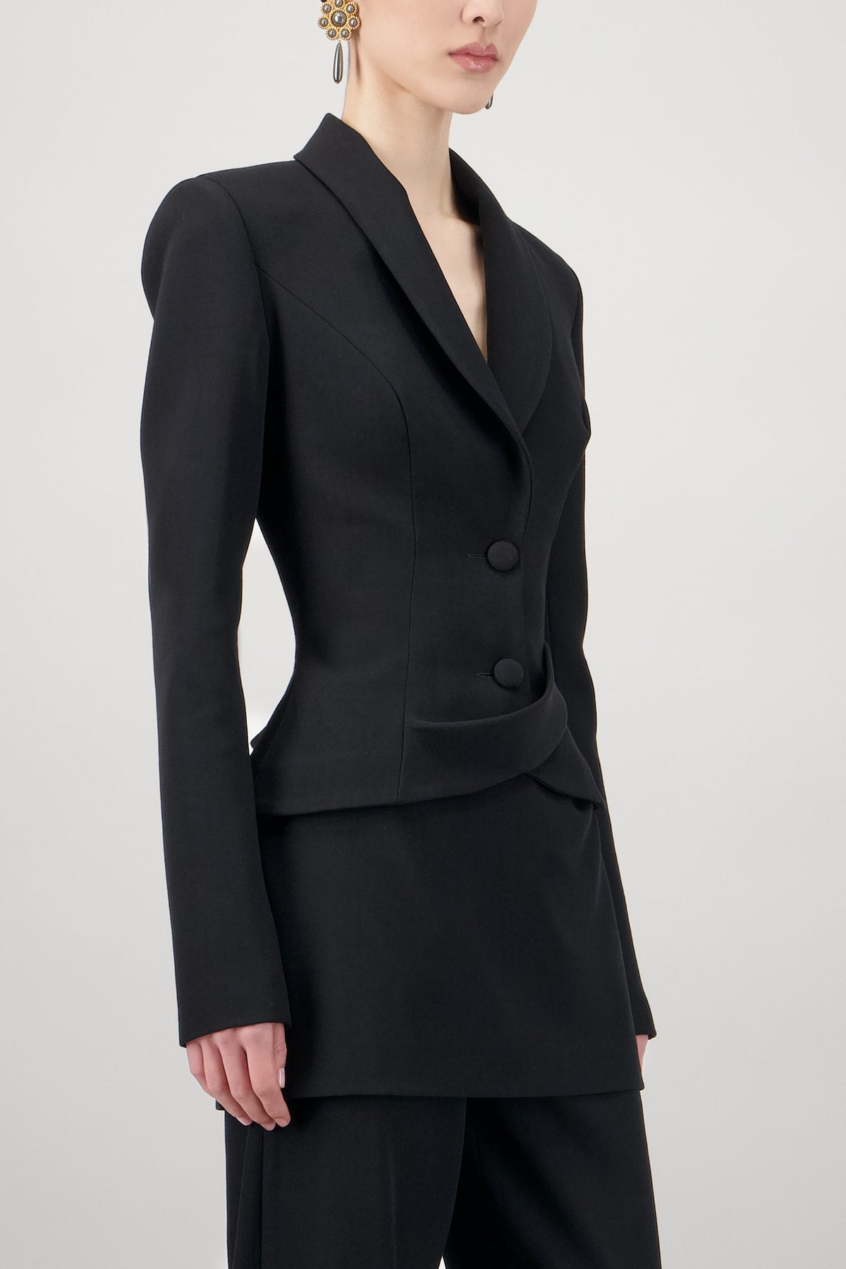 Wool jacket with structured shoulders, sculpted waist, lapel collar, button closure and asymmetric panel detailing.