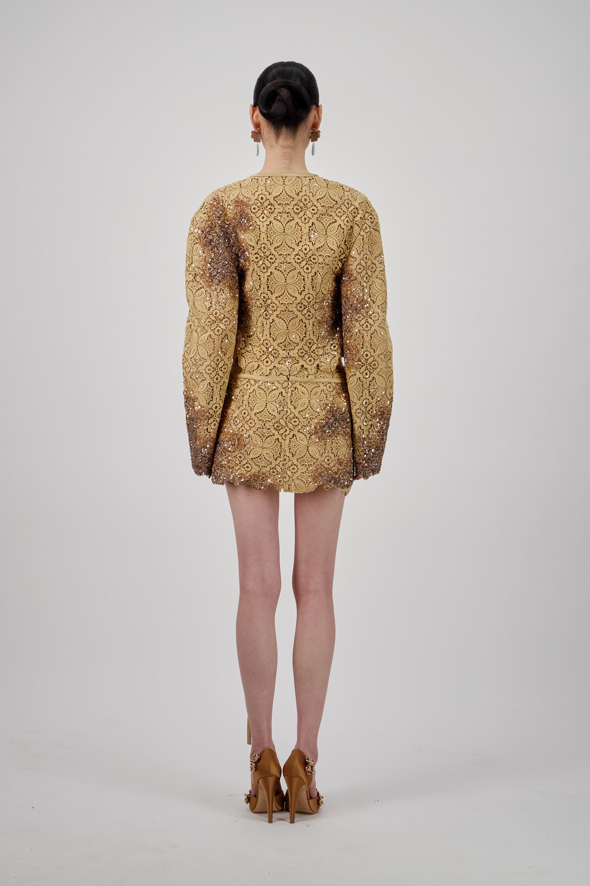 Lace embellished mini skirt with shimmering detailing, scalloped edges and long tie accents.
Cropped lace jacket with a deep V-neckline, long sleeves, shimmering embellishments and scalloped edges.