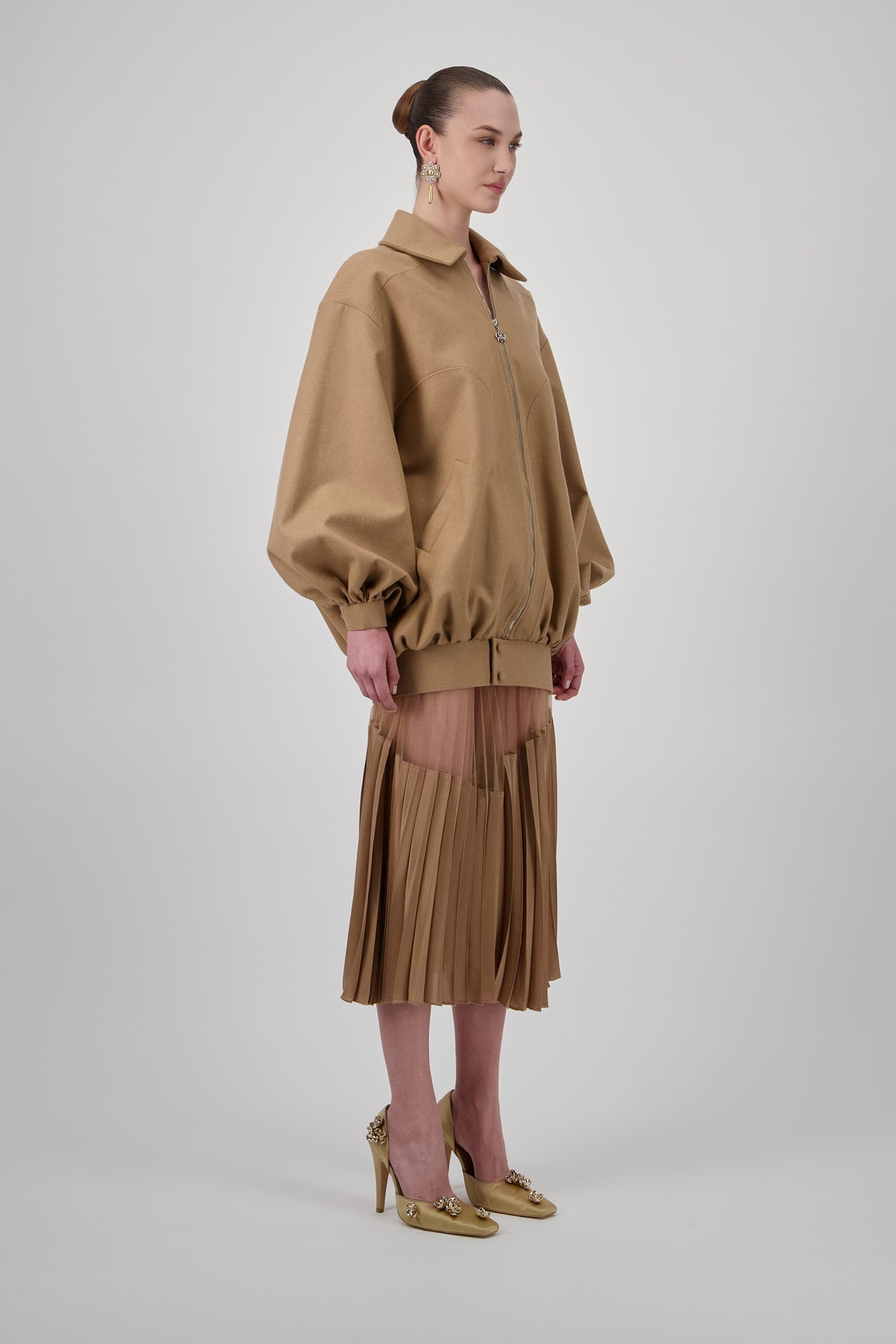 Tulle midi skirt with a sheer upper panel and structured pleated detailing.
Oversized wool jacket with a structured collar, voluminous sleeves, fitted hem and front zip closure.
