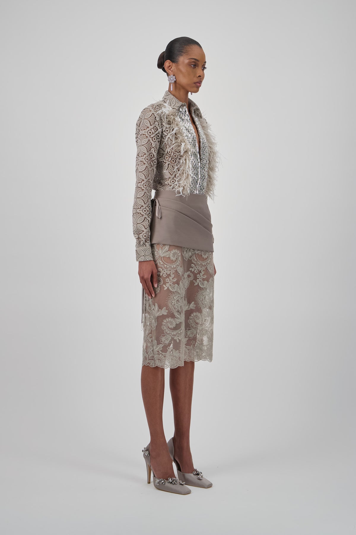 Lace floral midi skirt with a straight silhouette, intricate floral embroidery and scalloped hem.
Lace shirt with long sleeves, pointed collar, shimmering embellished front panel and soft feather trim.
