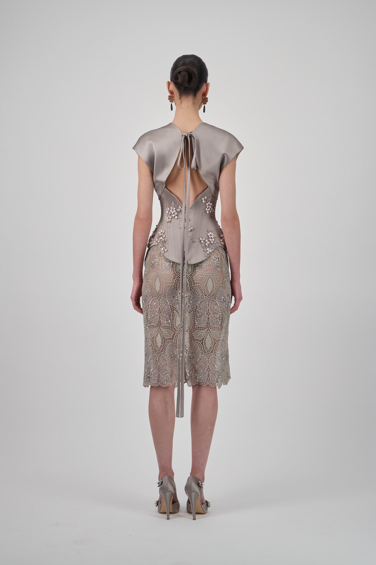 Sculpted corset top with floral embellishments, structured paneling and draped cap-sleeve detailing.
Lace short skirt with intricate floral patterns, delicate embellishments and a scalloped hem.