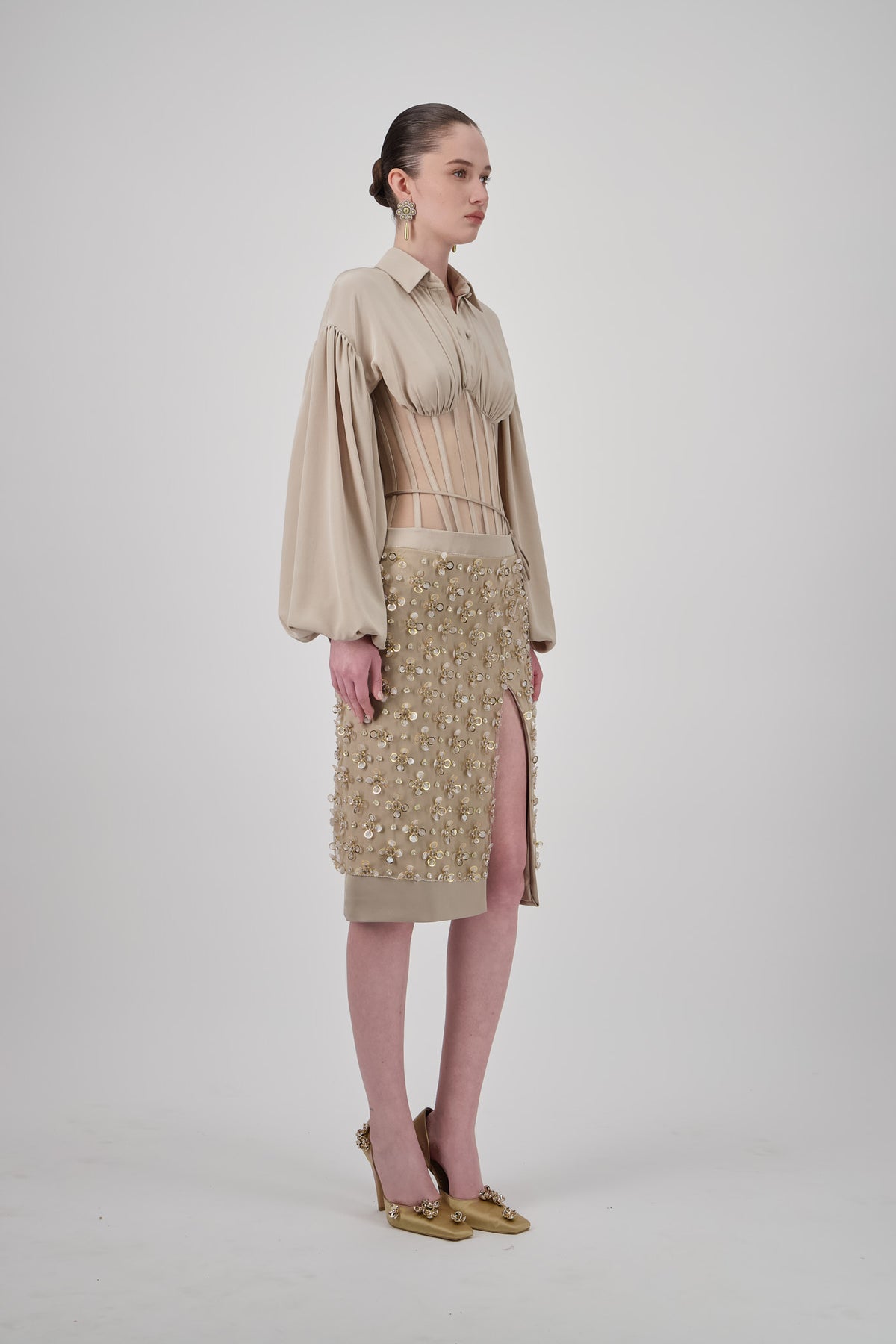 Layered short skirt with intricate embellishments, wrap-style construction, tie detail and front slit.
Georgette shirt with voluminous puff sleeves, pointed collar, gathered bust and sheer corset-inspired waist.